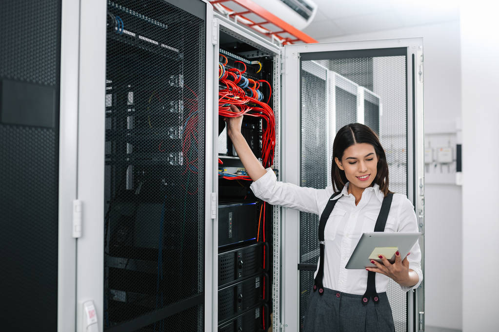 IT специалистка хостинг провайдера с планшетом в руках анализирует работу VDS серверов в дата центре